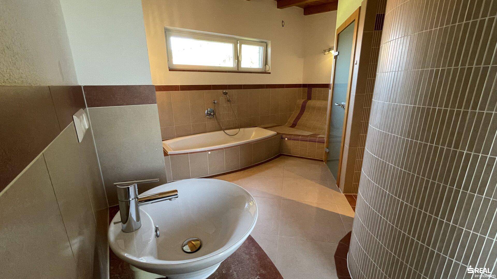 Geräumiges Badezimmer mit Badewanne, Waschbecken und Fenster für Tageslicht.