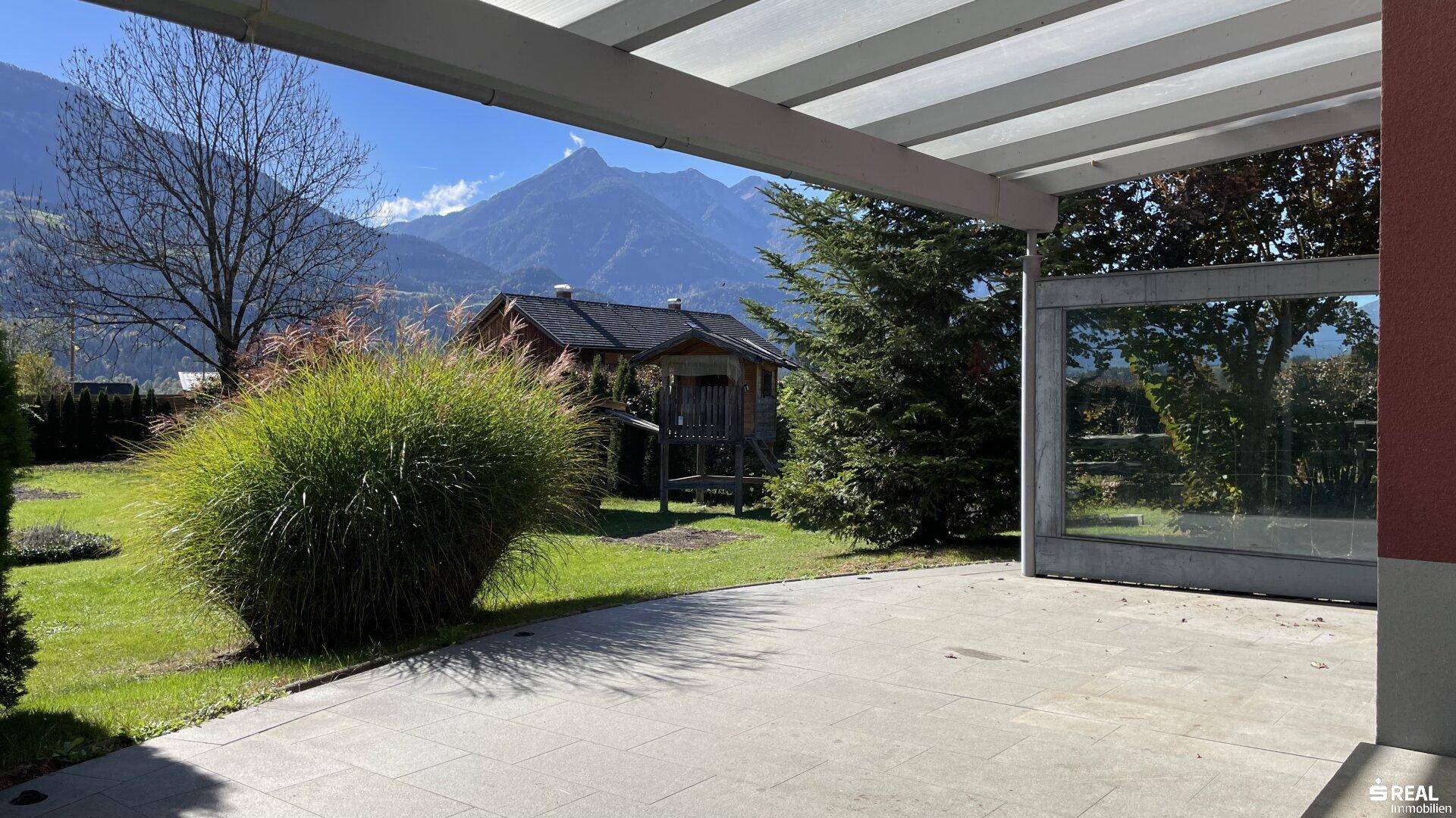 Große gepflasterte Terrasse mit Überdachung und beeindruckendem Bergblick.