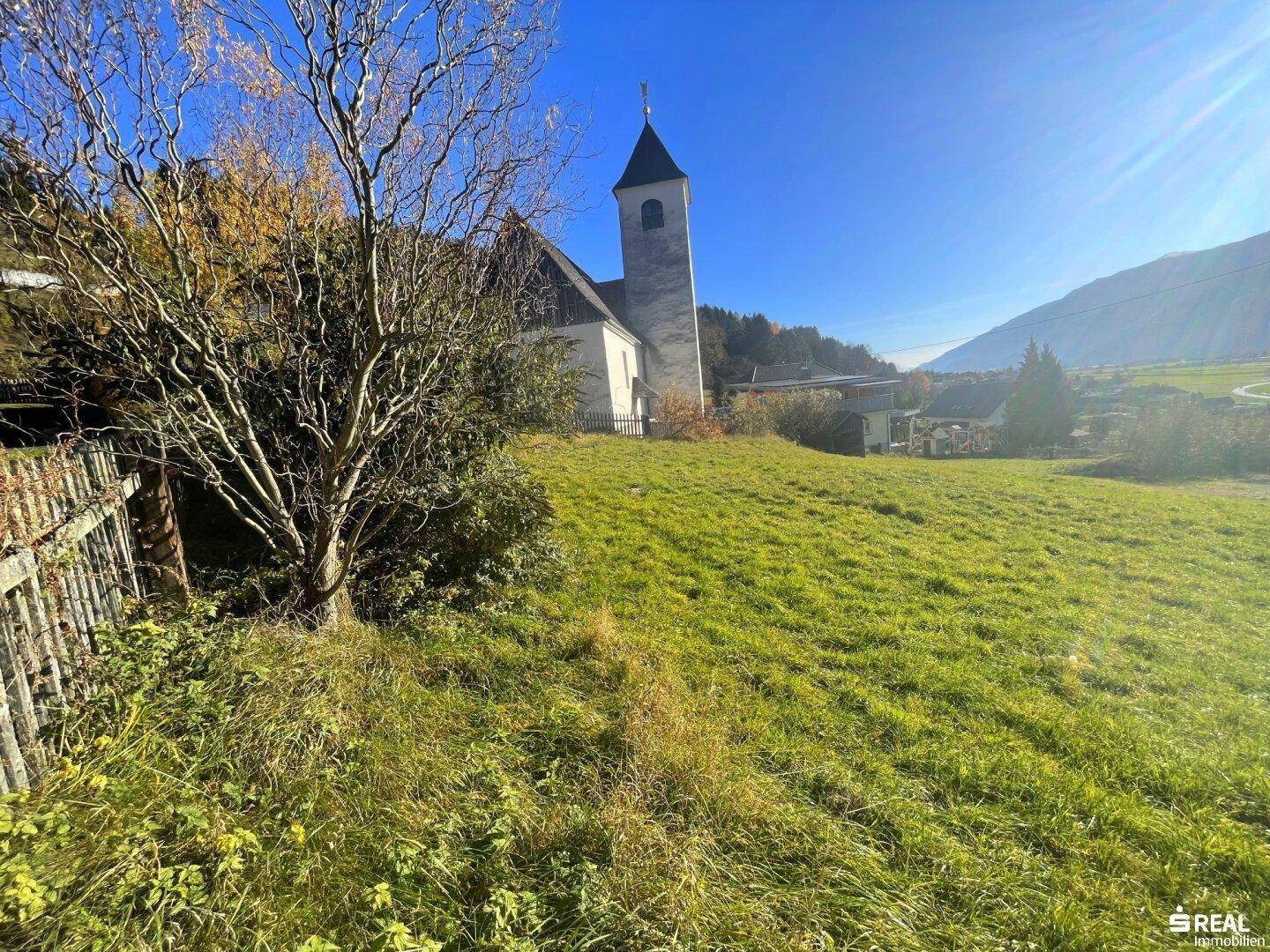 Panoramablick auf eine Kirche und die weite grüne Hügellandschaft an einem sonnigen Tag.