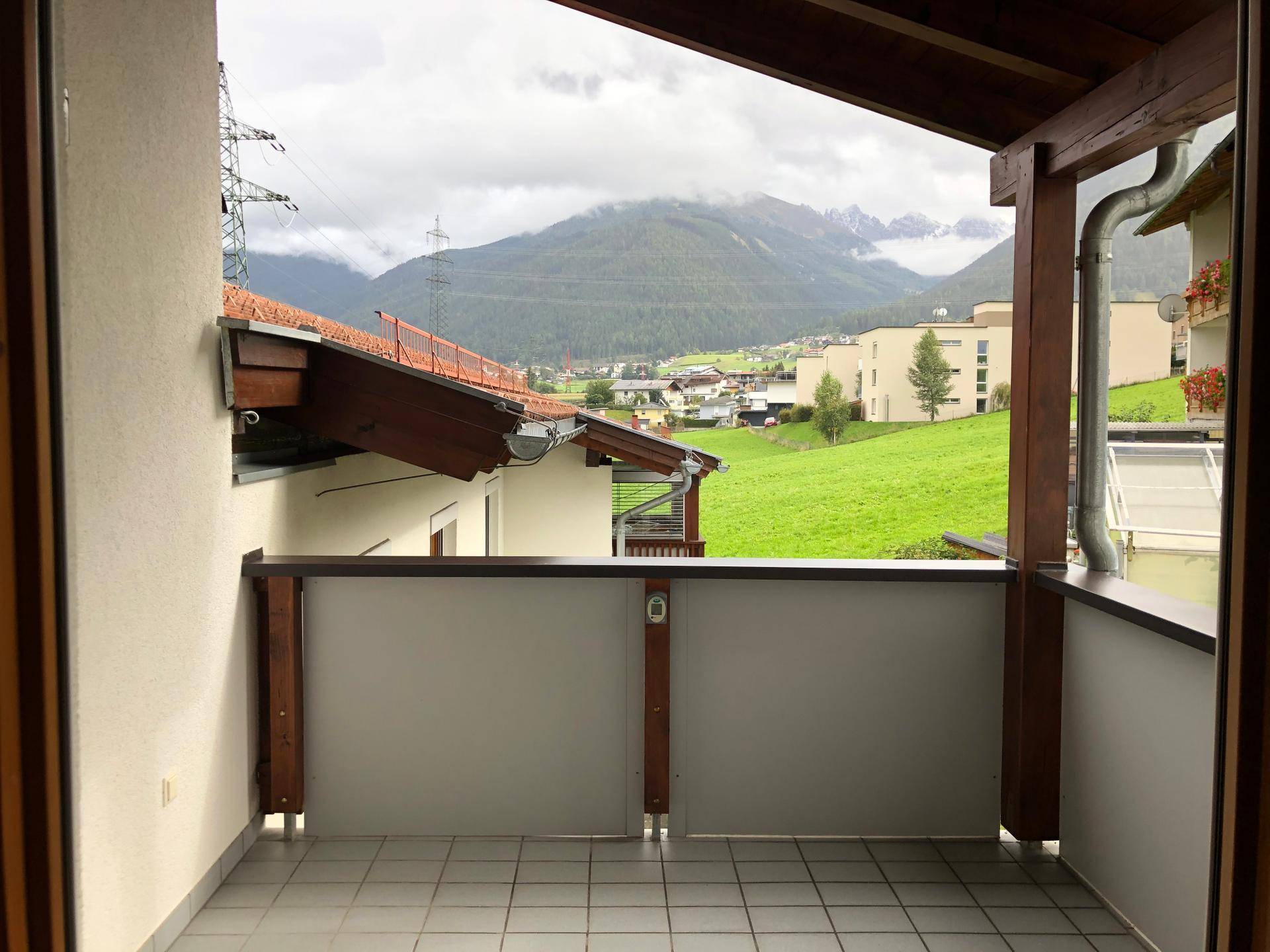 Balkon mit Fliesenboden und weitem Blick auf die umliegenden Berge und das Tal.
