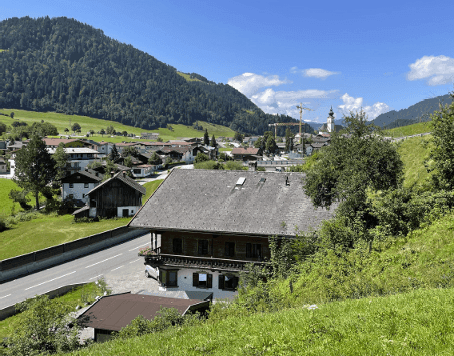 Traditionelles Haus in einem Bergdorf mit Blick auf die umliegende Landschaft und Kirche.