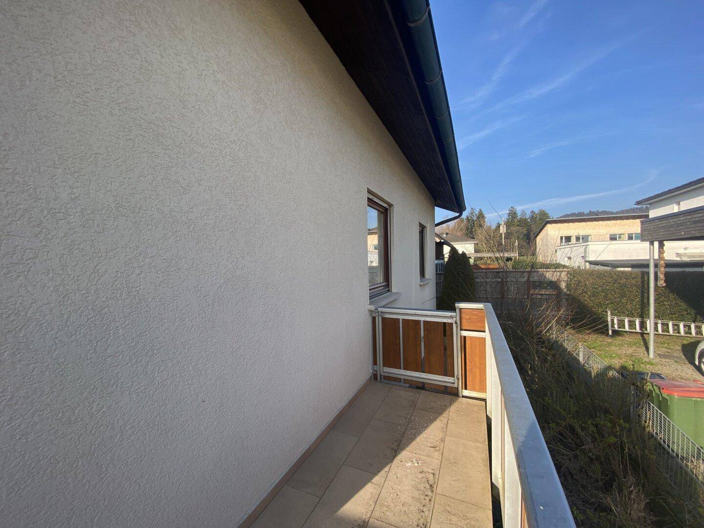 Schmaler Seitenbalkon mit Fliesenboden und einfacher Brüstung, ideal für frische Luft.