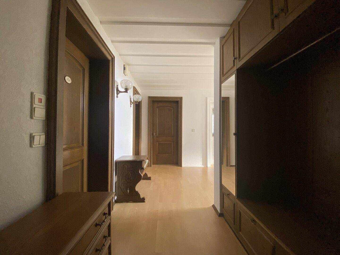 Langer Flur mit Holzparkett und Einbauschränken, der zu weiteren Räumen führt.