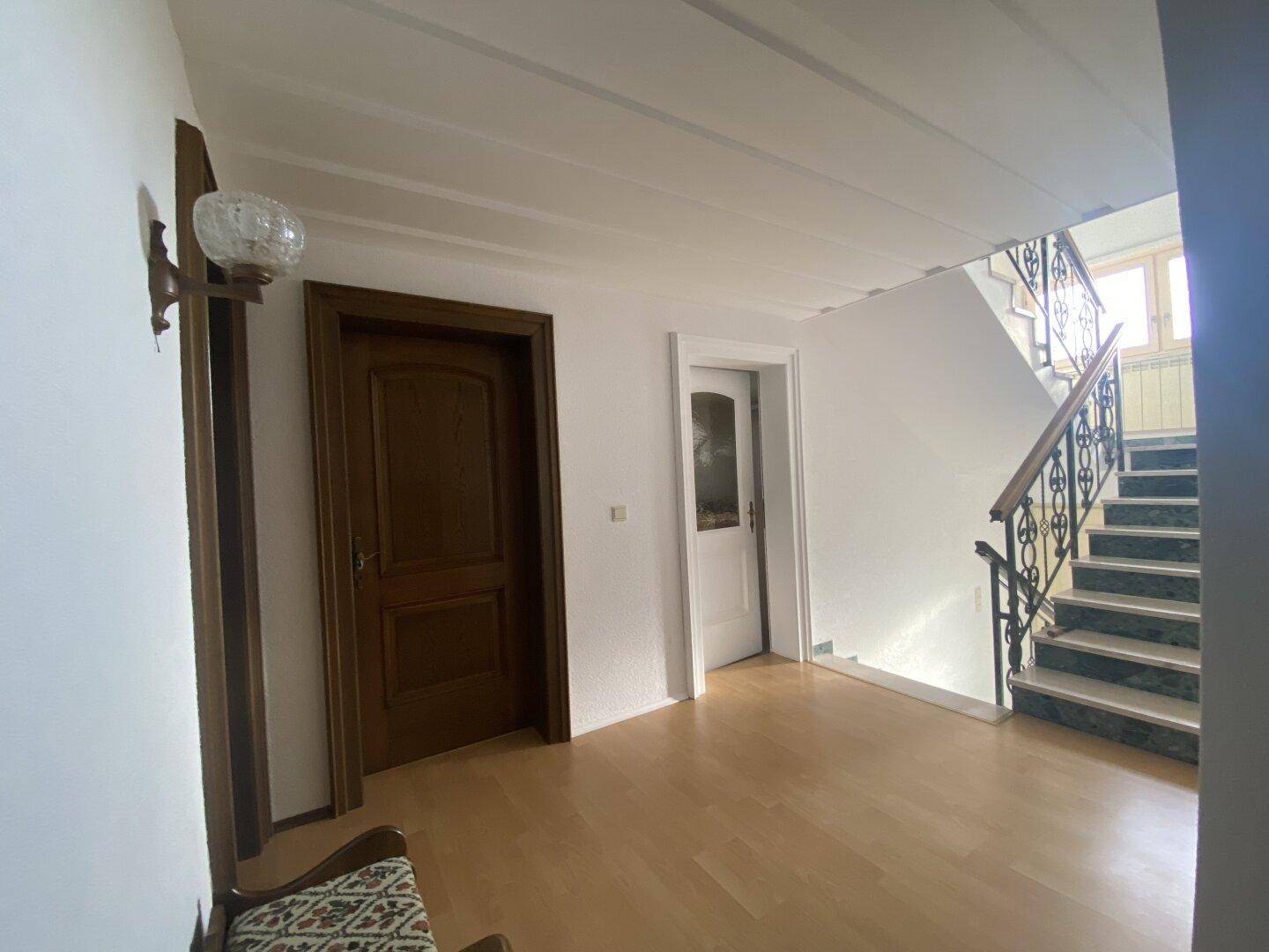 Geräumiger Flur mit Holzparkett und einer eleganten Treppe mit schmiedeeisernem Geländer.