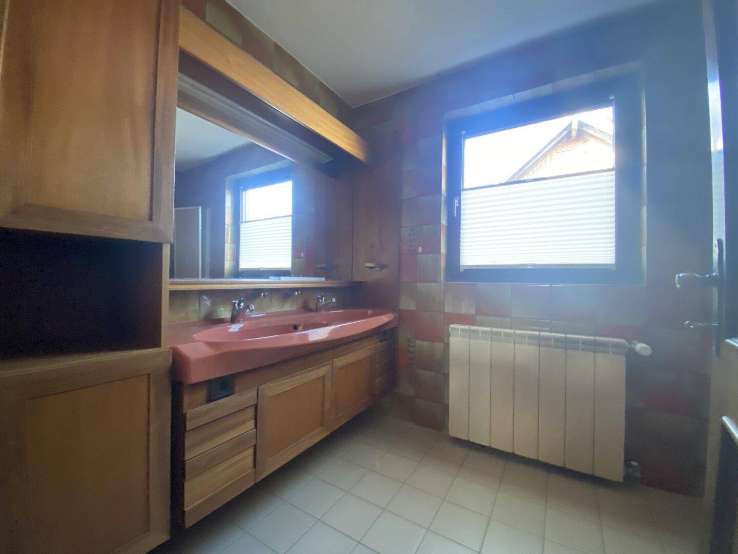 Badezimmer mit zwei Waschbecken, Spiegelschrank und Fenster für natürliche Belüftung.