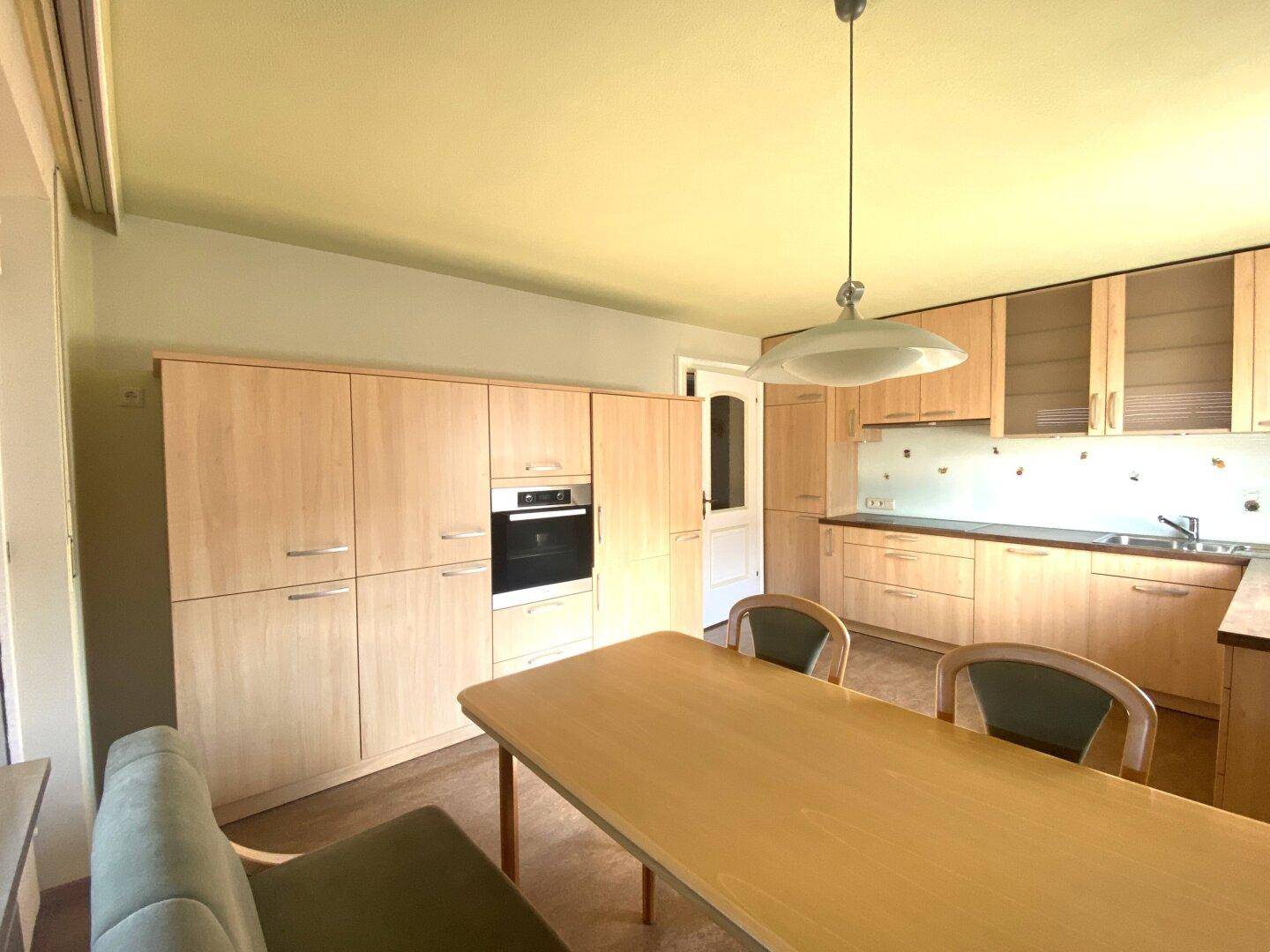 Helle Einbauküche mit Holzfronten, integrierten Geräten und Essbereich für die Familie.