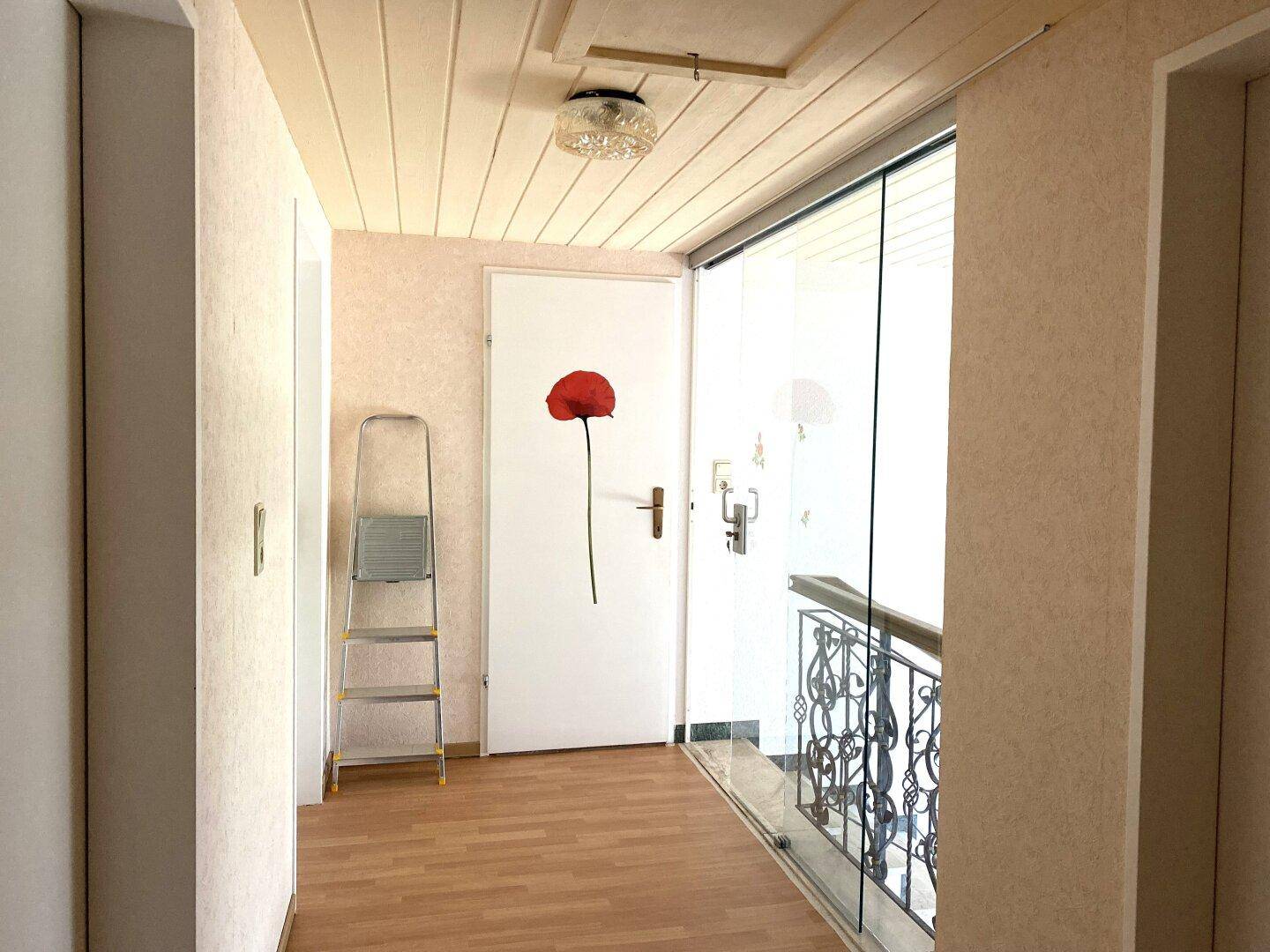 Heller Eingangsbereich mit Holzboden und einer Glastür, die zum Treppenhaus führt.