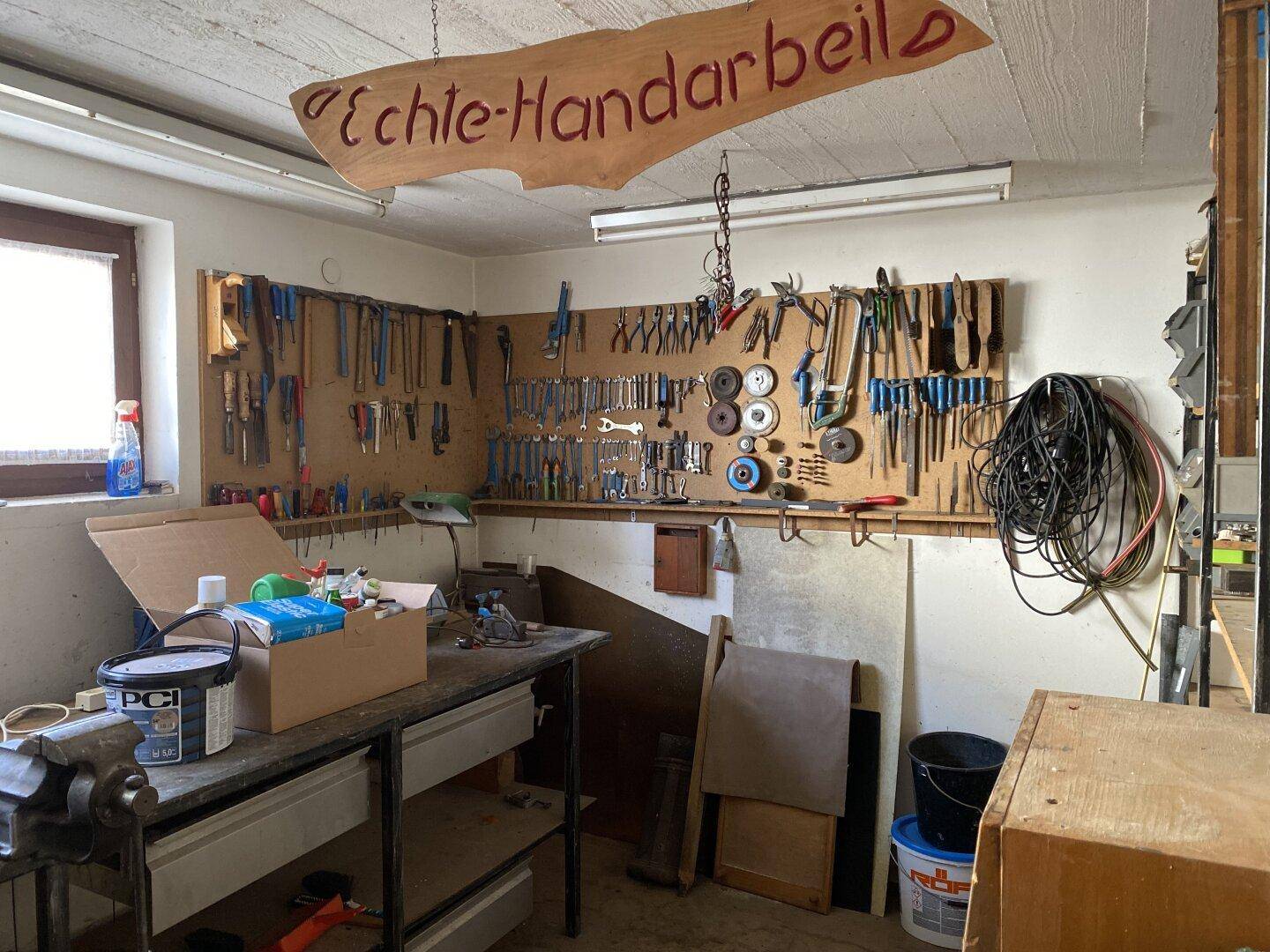 Werkstattraum mit zahlreichen Werkzeugen an der Wand und einer Werkbank für handwerkliche Arbeiten.