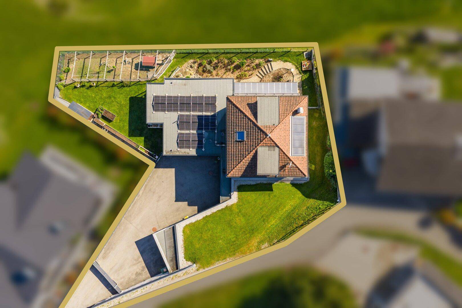 Luftaufnahme des Grundstücks mit eingezeichneter Grenze und Photovoltaikanlage auf dem Dach.