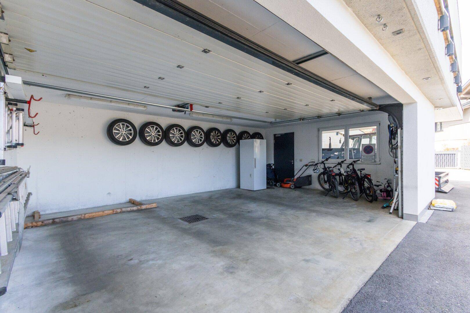 Geräumige Garage mit Betonboden, Stauraum und Fenstern für Tageslicht.