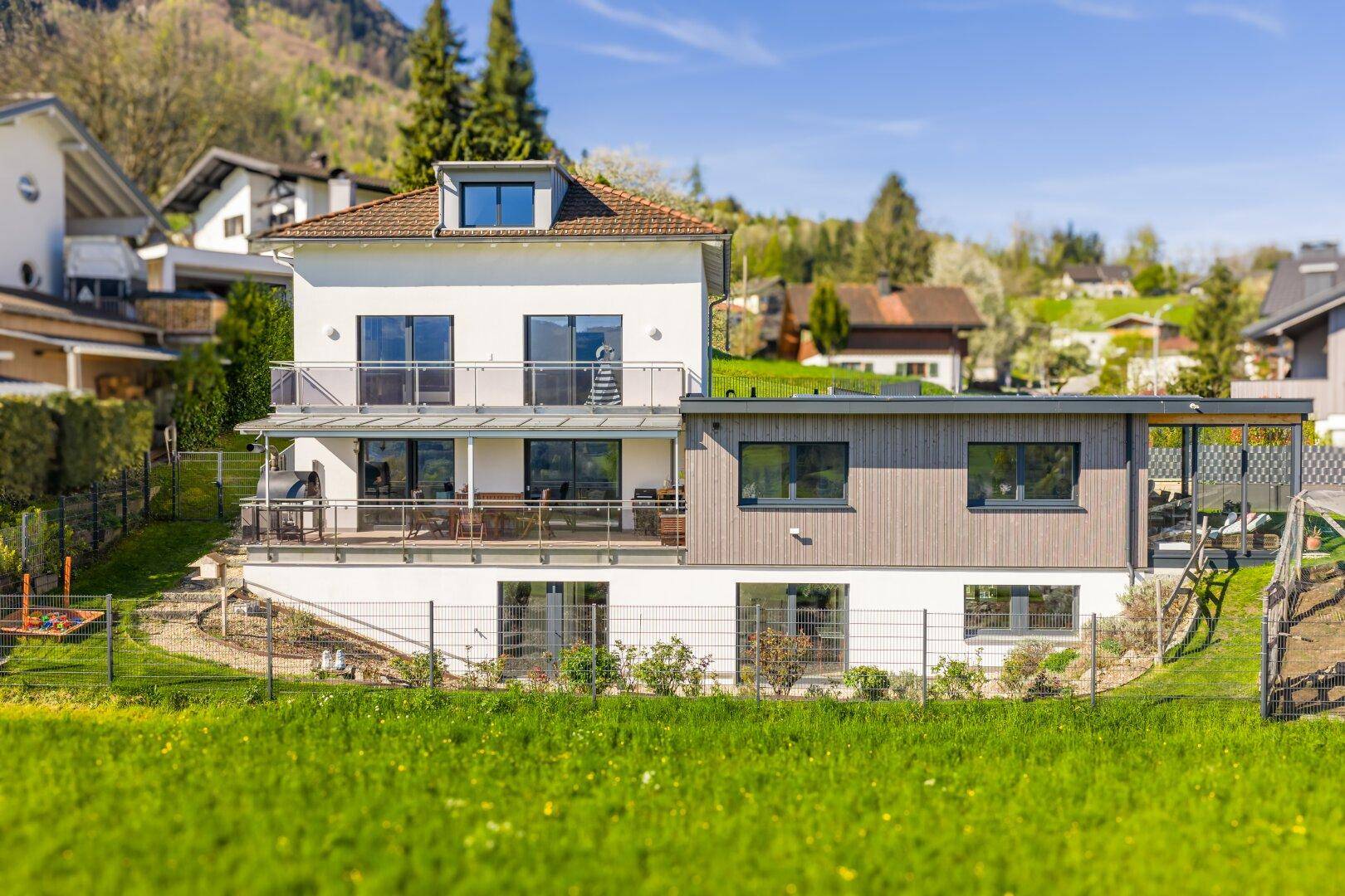 Modernes Wohnhaus mit mehreren Balkonen und weitem Blick auf die umliegende Berglandschaft.