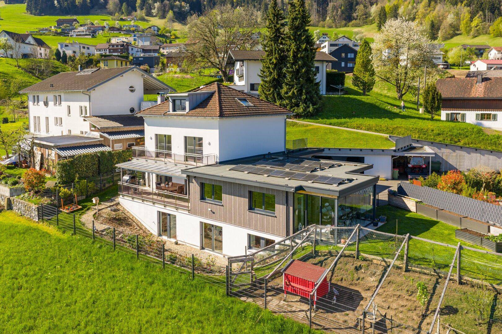Luftaufnahme des Anwesens mit Photovoltaikanlage auf dem Dach und terrassiertem Garten.