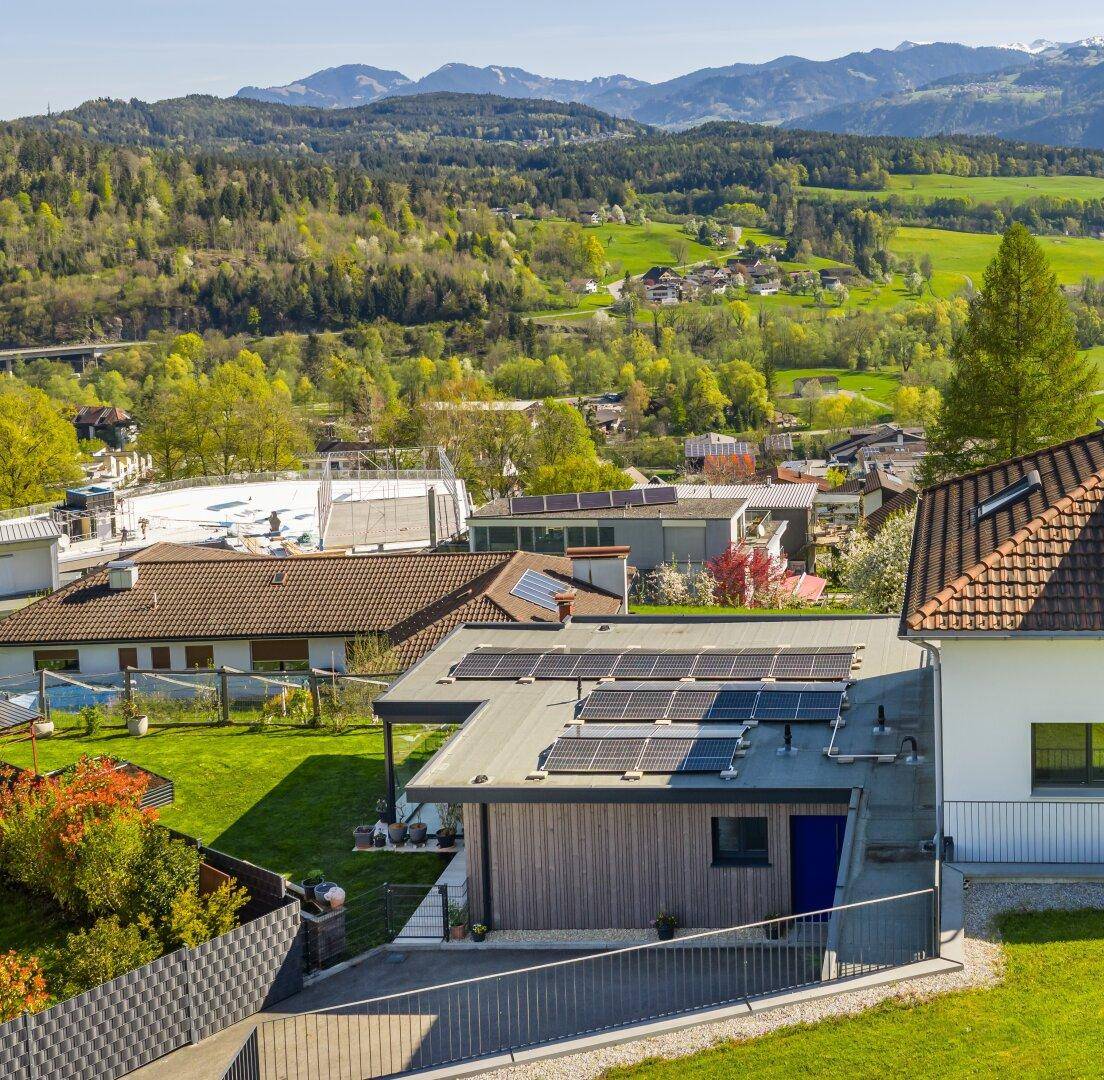 Dach des Gebäudes mit Photovoltaikanlage und weitem Blick auf die Berglandschaft.