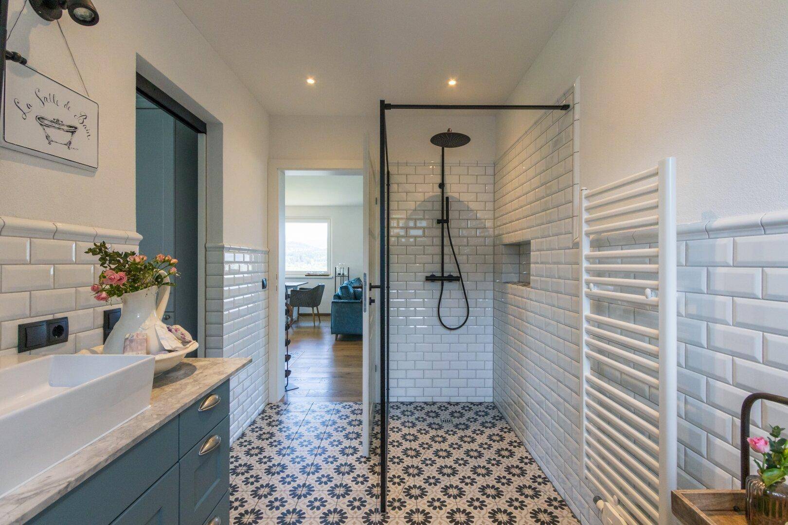 Badezimmer mit begehbarer Dusche, gemusterten Bodenfliesen und Handtuchheizkörper.