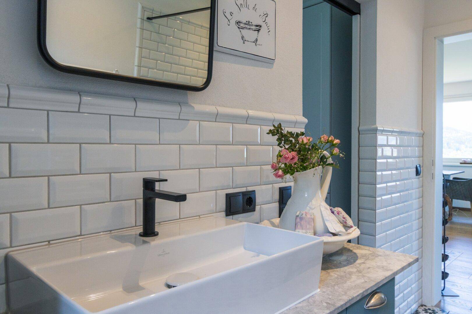 Detailaufnahme des Waschbeckens im Badezimmer mit weißen U-Bahn-Fliesen.