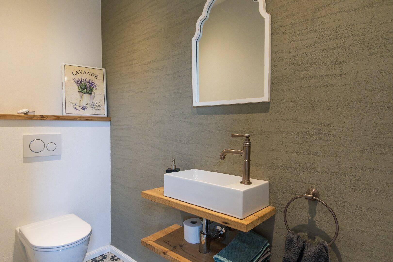 Stilvolles Gäste-WC mit modernem Waschbecken und dekorativem Spiegel.