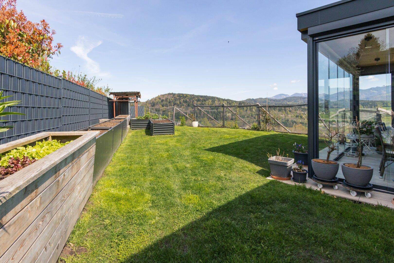 Gepflegter Gartenbereich mit Hochbeeten und weitem Blick auf die Berge.