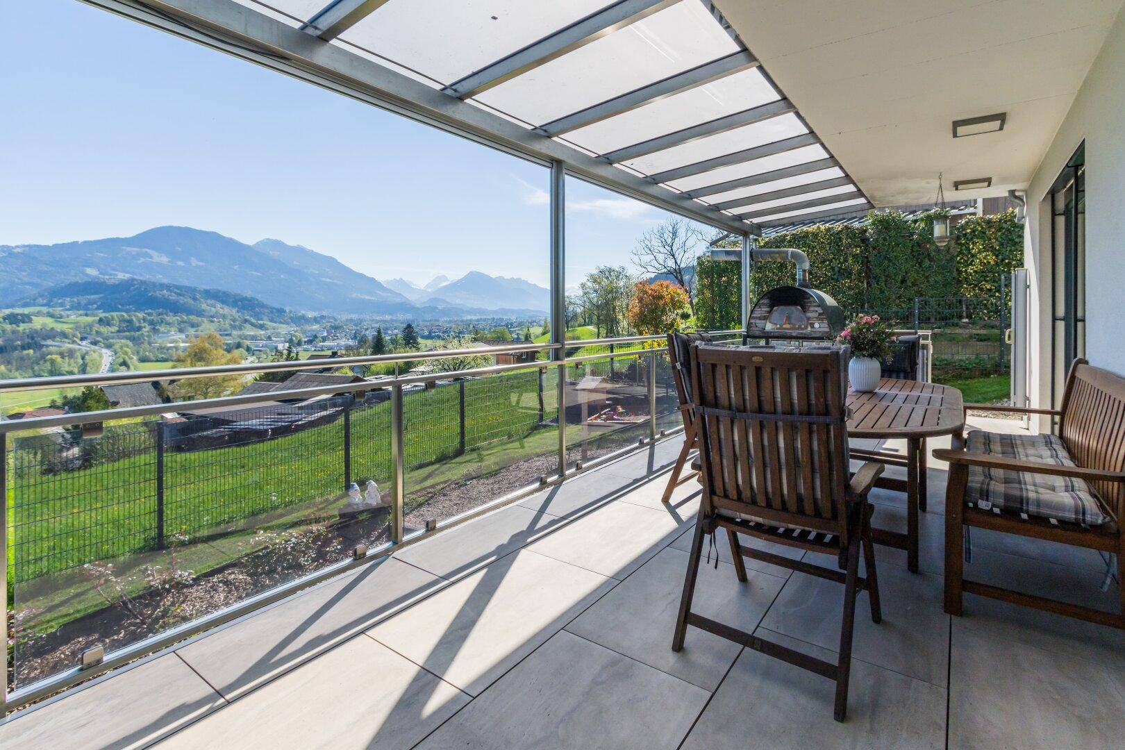 Geräumige Terrasse mit Esstisch, Grill und Panoramablick auf die umliegenden Berge.