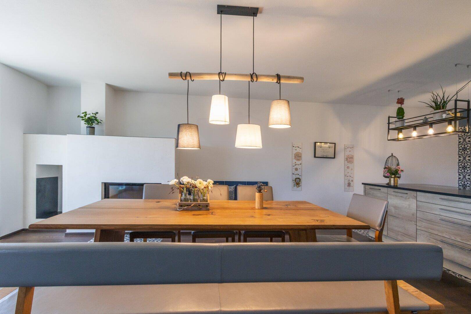 Gemütlicher Essbereich mit Holztisch, modernen Hängelampen und Blick auf den Kamin.