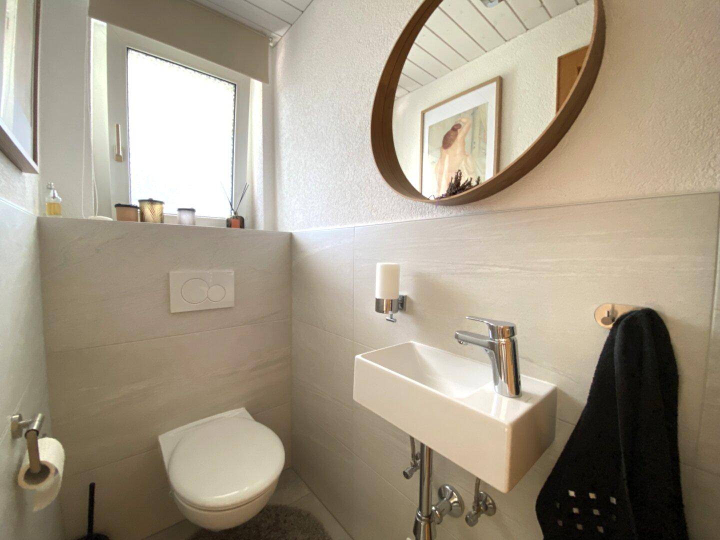 Modernes Gäste-WC mit wandhängendem WC, kleinem Waschbecken und Fenster.