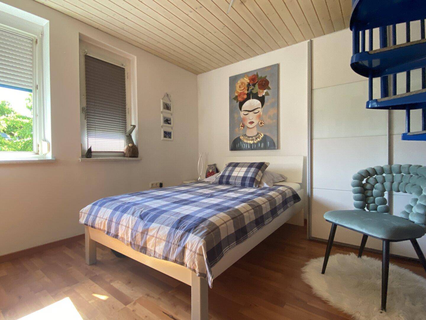 Gemütliches Schlafzimmer mit Holzbalkendecke, Einzelbett und Fenster.