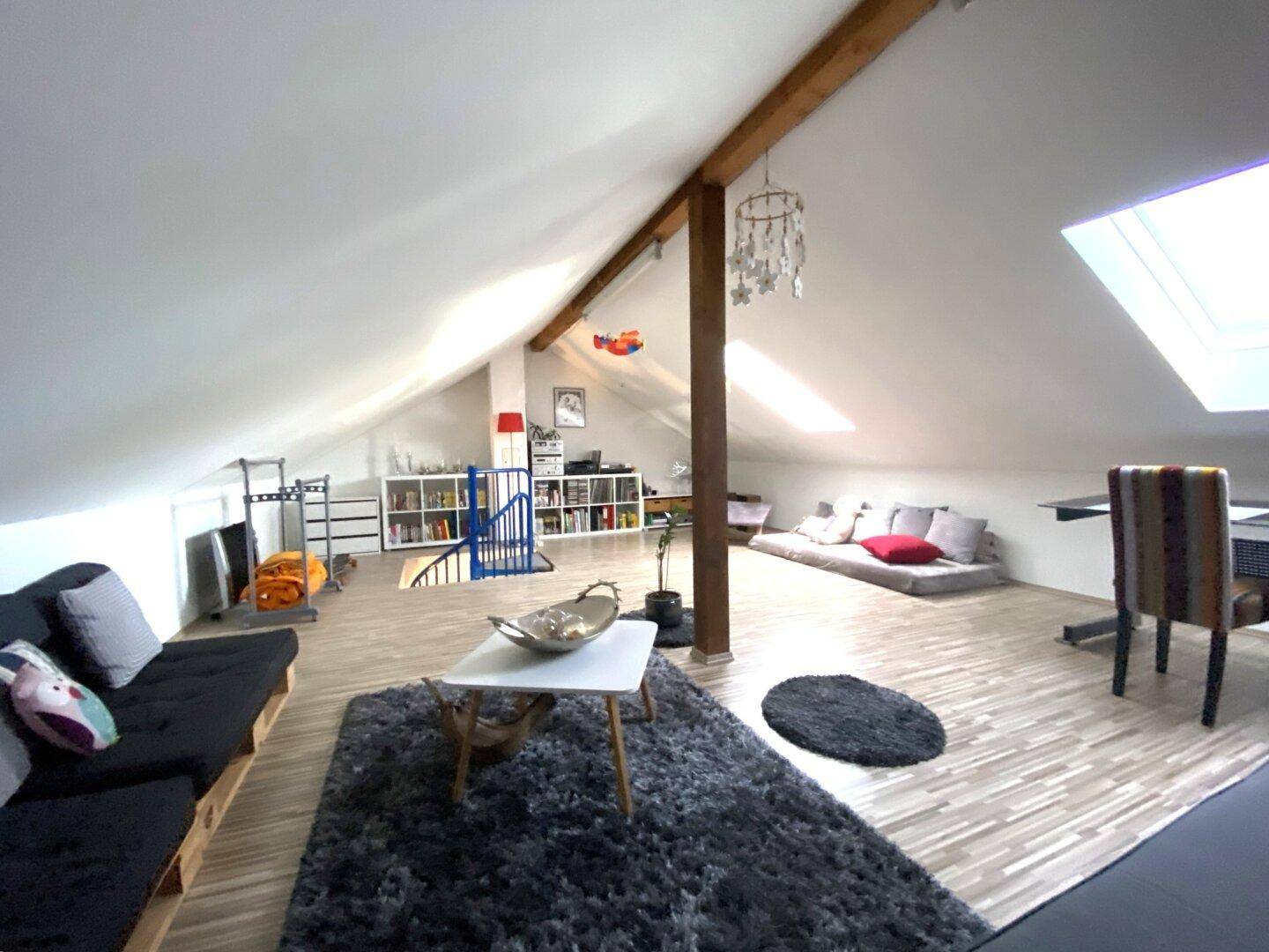 Heller Dachboden mit viel Platz, Dachschrägen und einer Wendeltreppe.