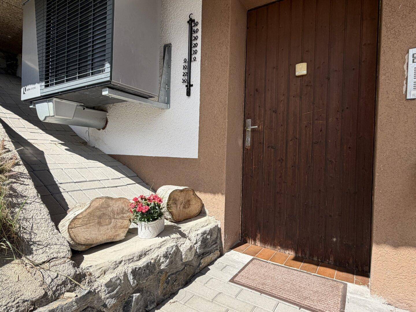 Rustikale Holzeingangstür mit Thermometer und dekorativen Holzelementen.