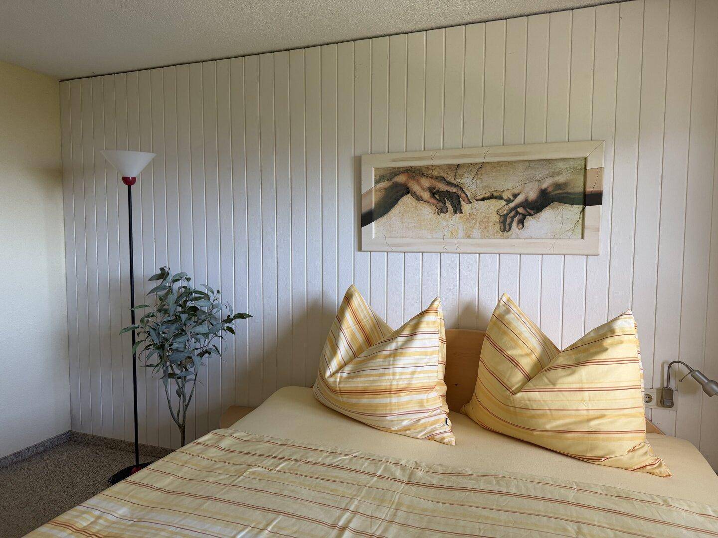 Schlafzimmer mit Doppelbett und heller Holzvertäfelung, gemütlich eingerichtet.