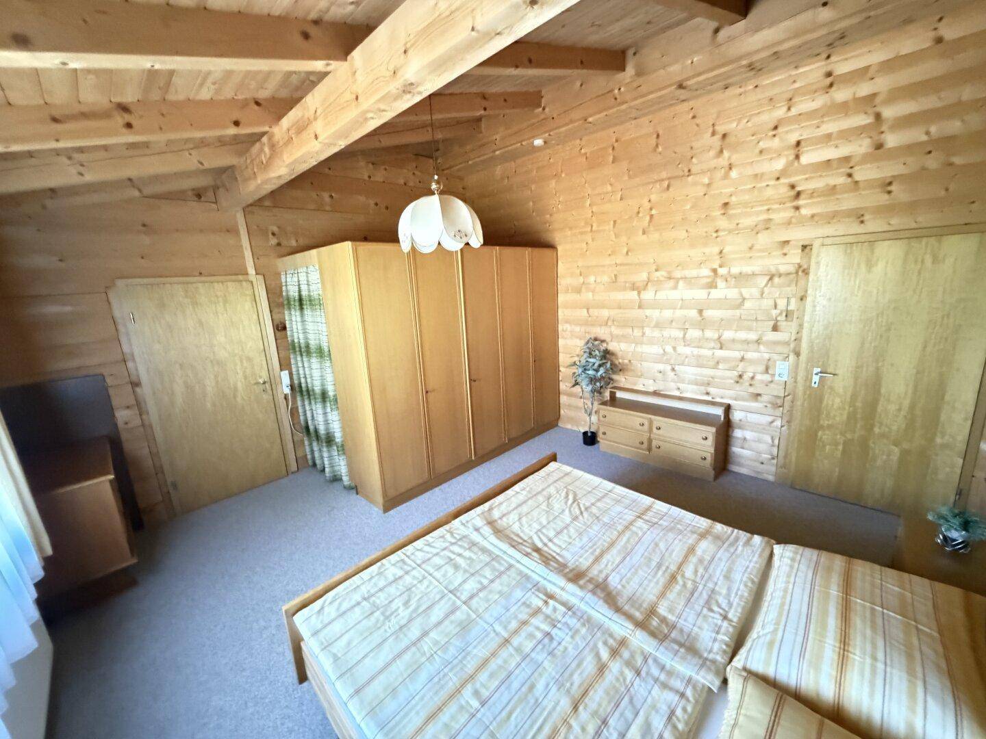 Geräumiges Schlafzimmer mit viel Holz, großem Kleiderschrank und Kommode.