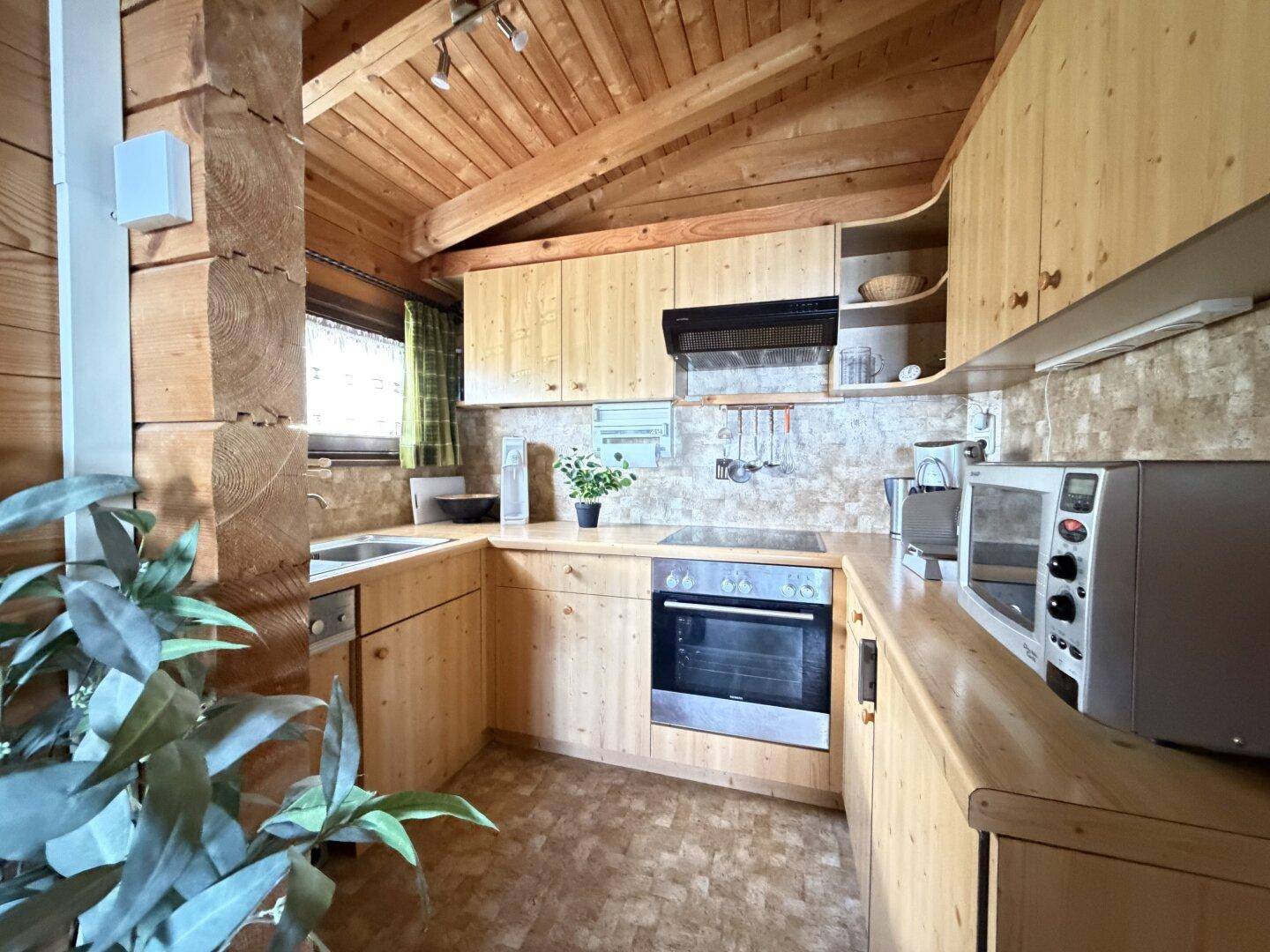 Rustikale Küche mit Holzschränken, Einbauherd, Induktionskochfeld und Mikrowelle.