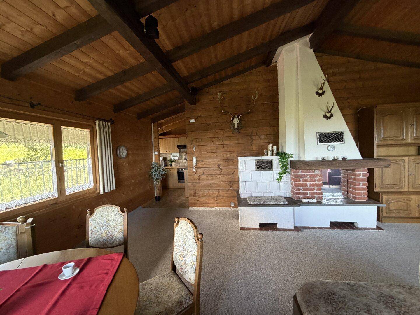 Gemütliches Wohnzimmer mit großem Kamin, Kachelofen und traditionellen Hirschgeweih-Dekorationen.