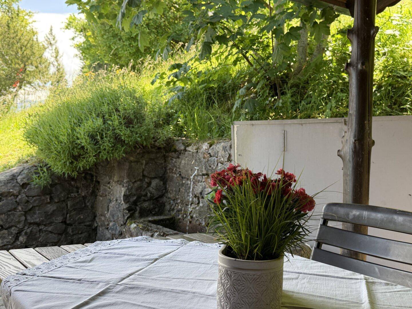 Detailansicht eines gedeckten Tisches auf der Terrasse mit grüner Umgebung.