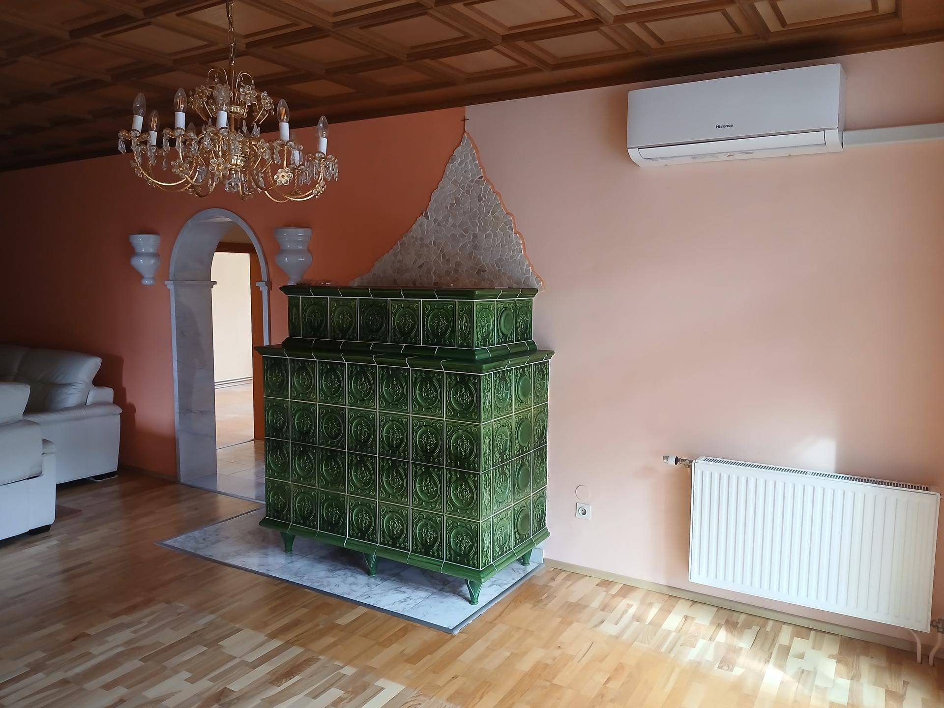 Gemütliches Wohnzimmer mit traditionellem Kachelofen, Holzkassettendecke und Parkettboden.