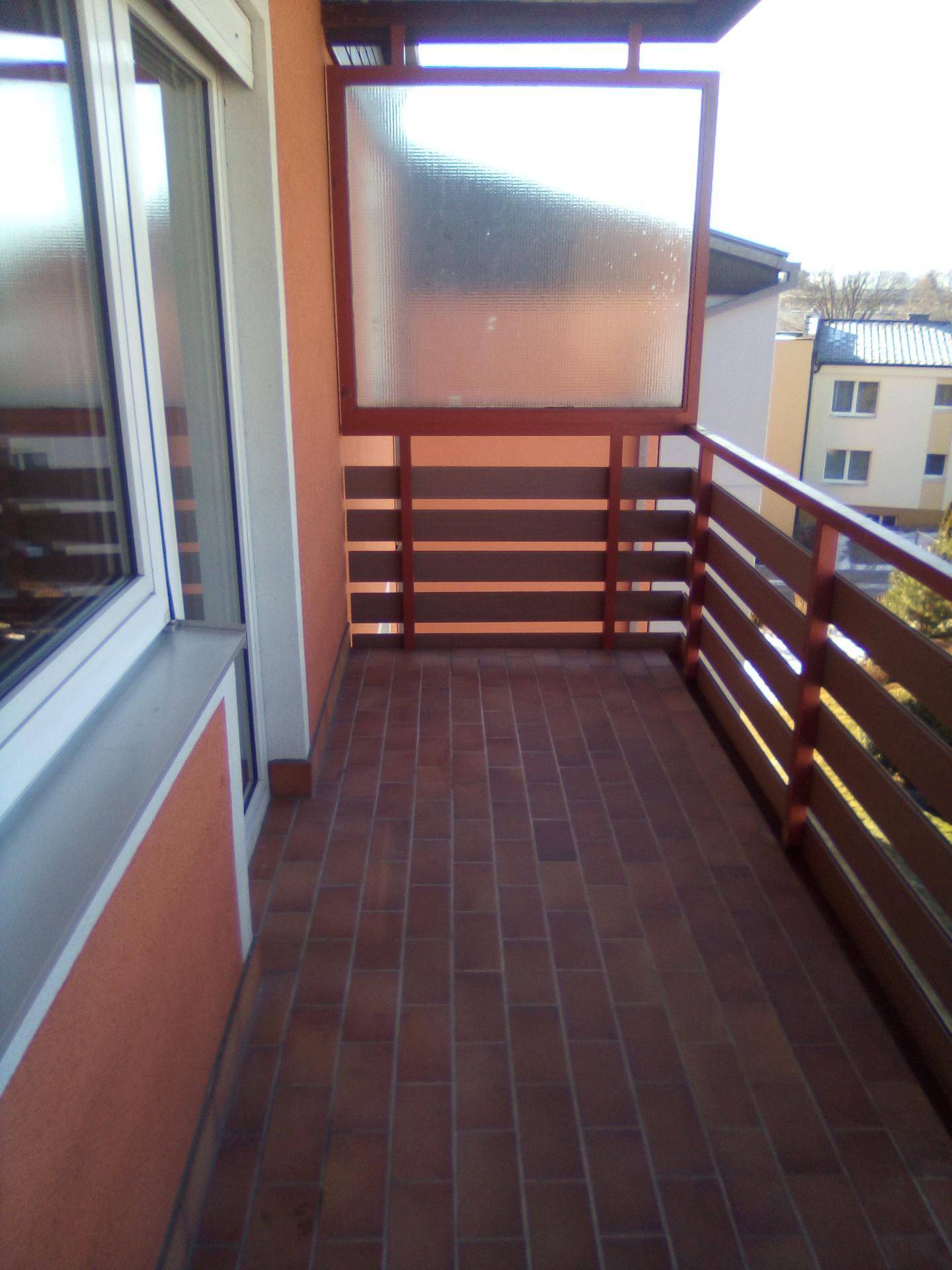 Gemütlicher Balkon mit Fliesenboden und Holzgeländer, ideal für entspannte Stunden im Freien.