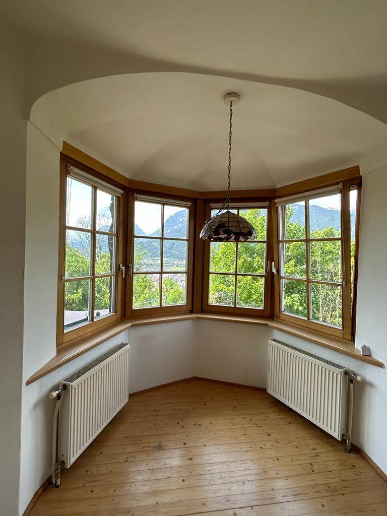 Heller Erkerbereich mit Holzdielenboden und Panoramablick auf die umliegende Berglandschaft.