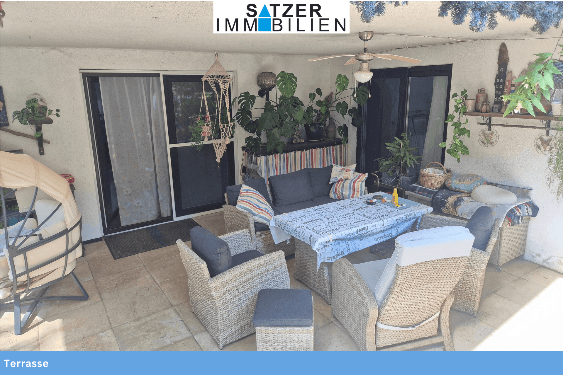 Große, möblierte Terrasse mit Sitzgelegenheiten, Pflanzen und Deckenventilator.