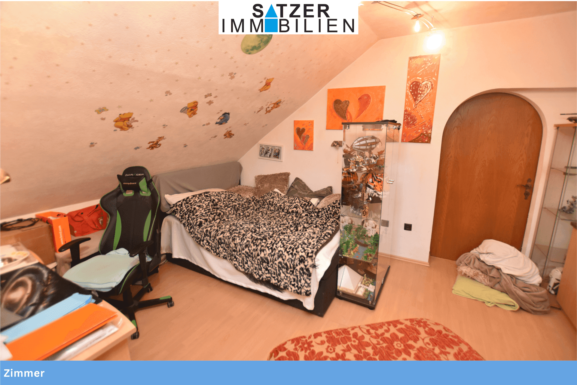 Helles Zimmer im Dachgeschoss mit schräger Decke, Bett und verspielter Wanddekoration.
