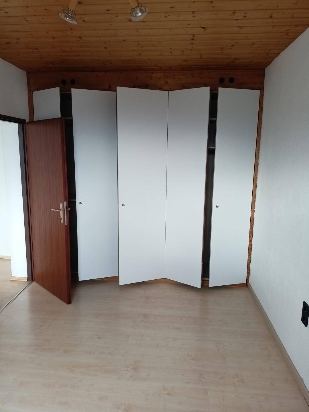 Schlafzimmer mit praktischen Einbauschränken, Laminatboden und Holzdecke.