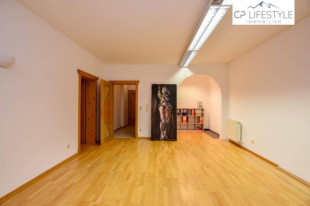 Großer Büroraum mit Holzfußboden, einem dekorativen Gemälde und einem Durchgang mit Rundbogen.