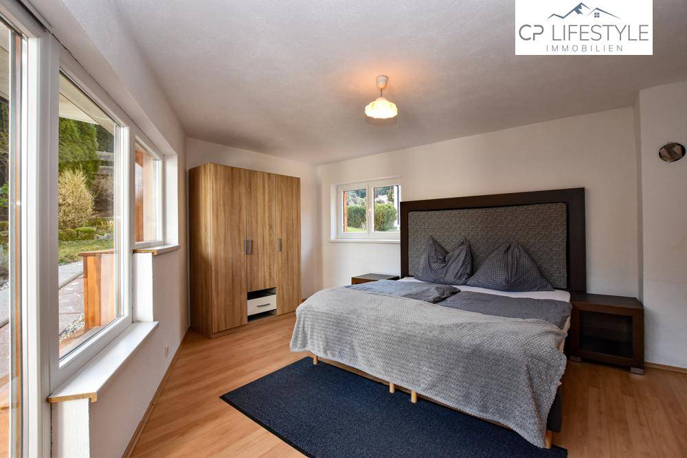 Geräumiges Schlafzimmer mit Doppelbett, Holzschrank und direktem Zugang zum Garten.