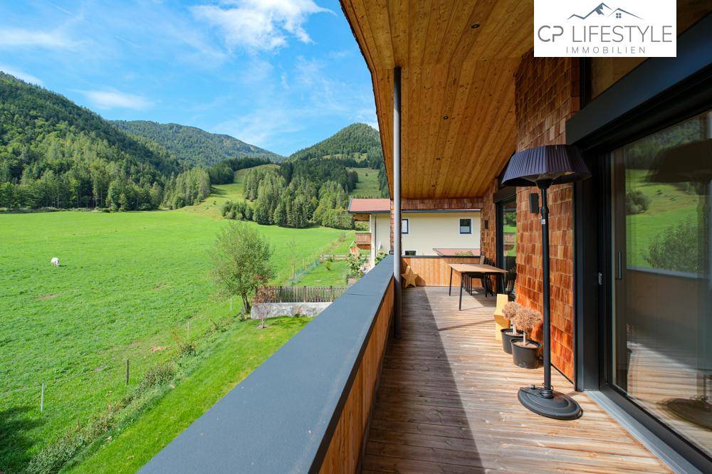 Geräumiger Balkon mit Holzboden und weitem Blick auf die grüne Berglandschaft.