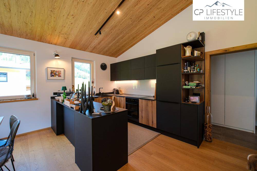 Moderne Einbauküche in Schwarz mit Holzdetails, Kochinsel und viel Stauraum.
