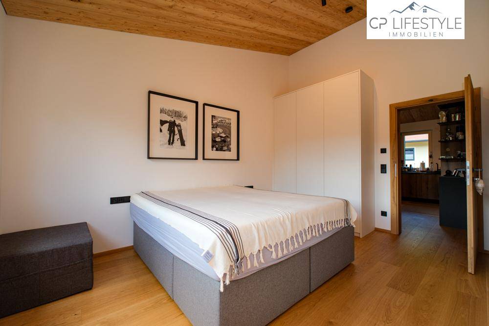 Gemütliches Schlafzimmer mit Holzboden, weißem Kleiderschrank und Zugang zur Küche.