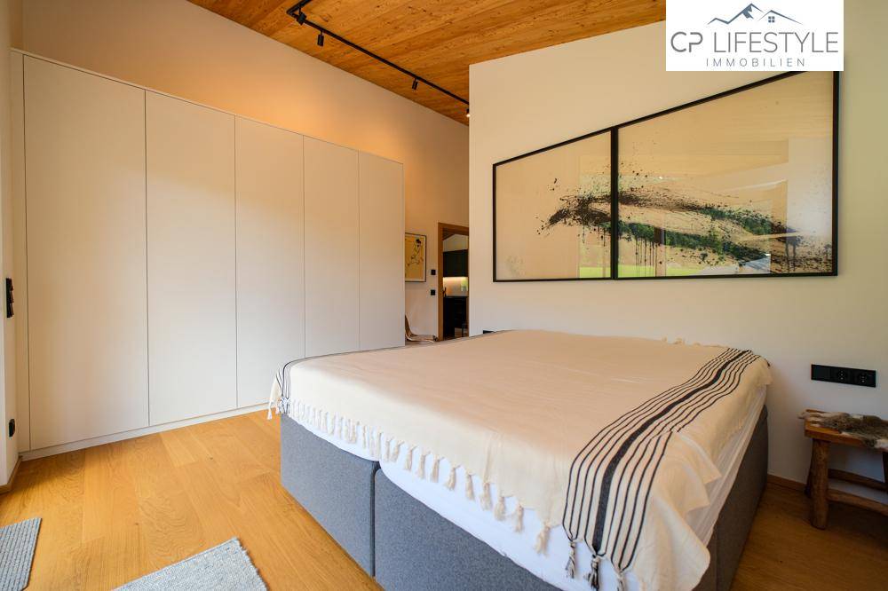 Helles Schlafzimmer mit Holzboden, Einbauschränken und modernem Doppelbett.