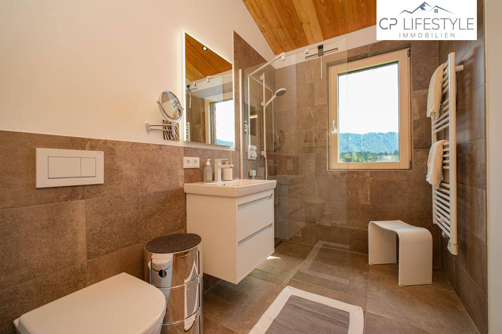 Modernes Badezimmer mit großen Fliesen, ebenerdiger Dusche und beheiztem Handtuchhalter.