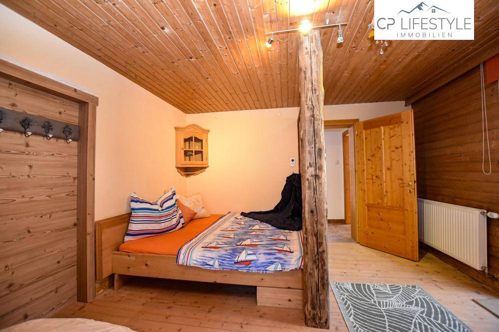 Rustikales Schlafzimmer mit Holzbalkendecke, Einzelbett und Holzelementen.