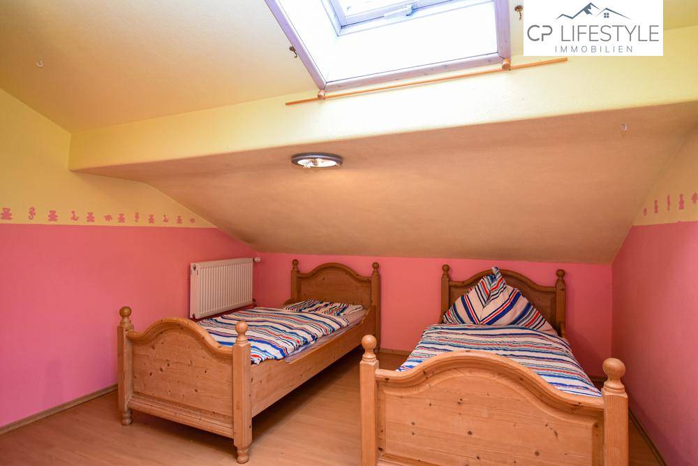 Farbenfrohes Schlafzimmer im Dachgeschoss mit Dachfenster und zwei Einzelbetten.