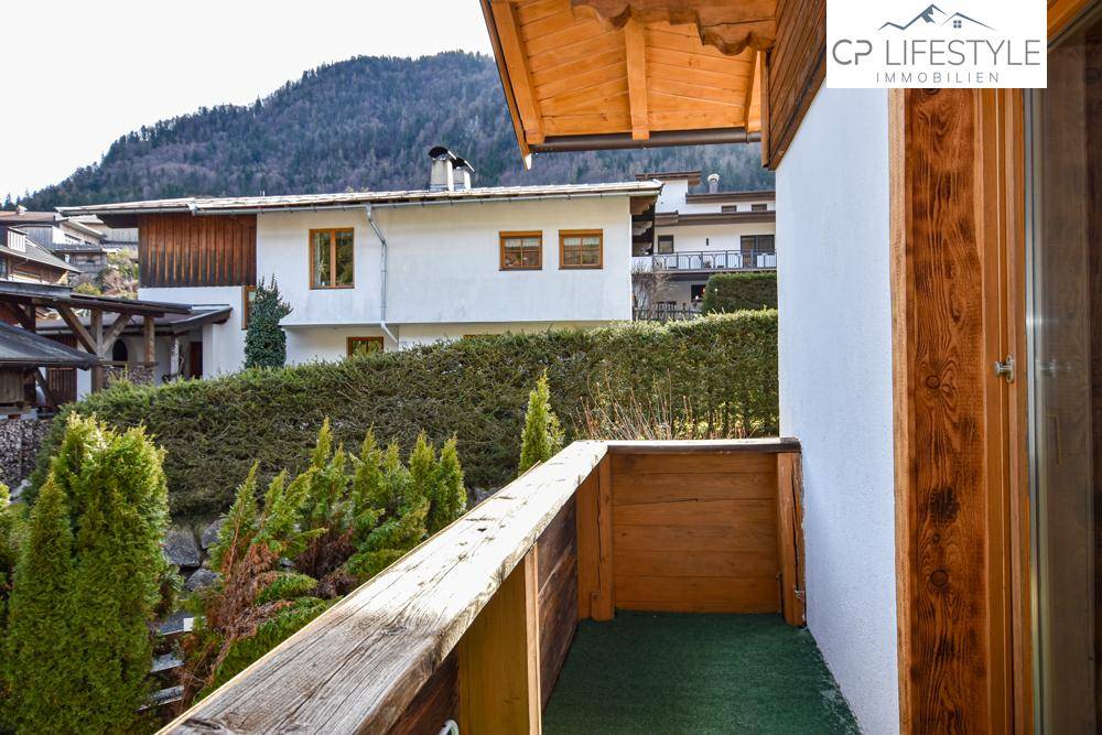 Kleiner Balkon mit Holzgeländer und Kunstrasen, ideal für frische Luft.