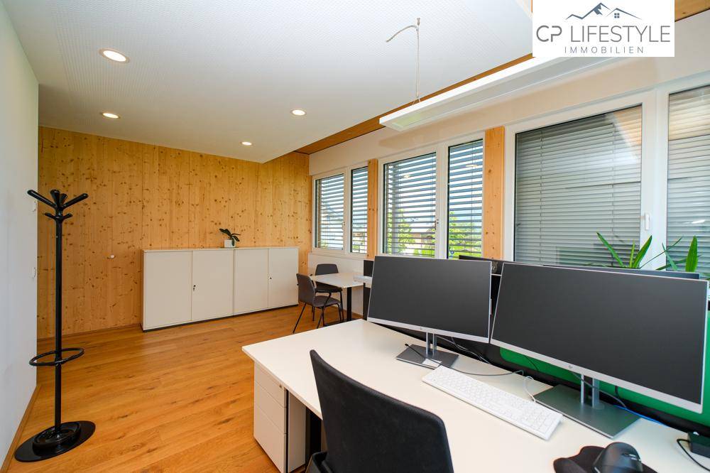 Modernes Büro mit Holzwandverkleidung, Schreibtischen und Blick auf die grüne Umgebung.