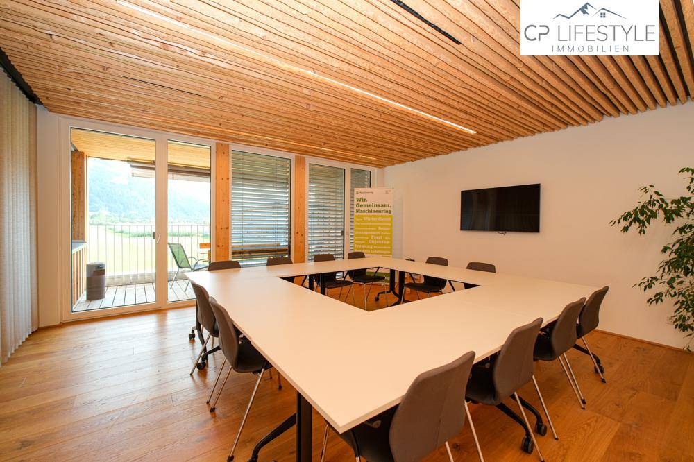 Großer Konferenzraum mit Holzboden, Holzdach und Zugang zu einem Balkon mit Bergblick.
